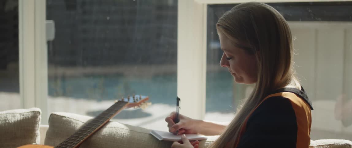 A woman writes song lyrics on the couch