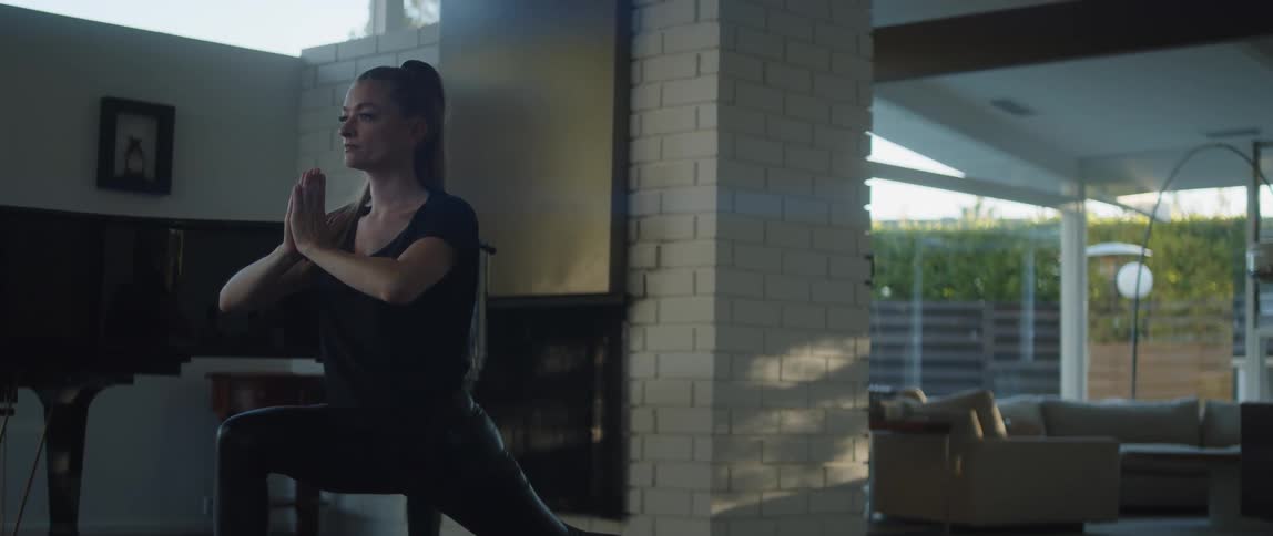 A young white woman is doing yoga inside of her house
