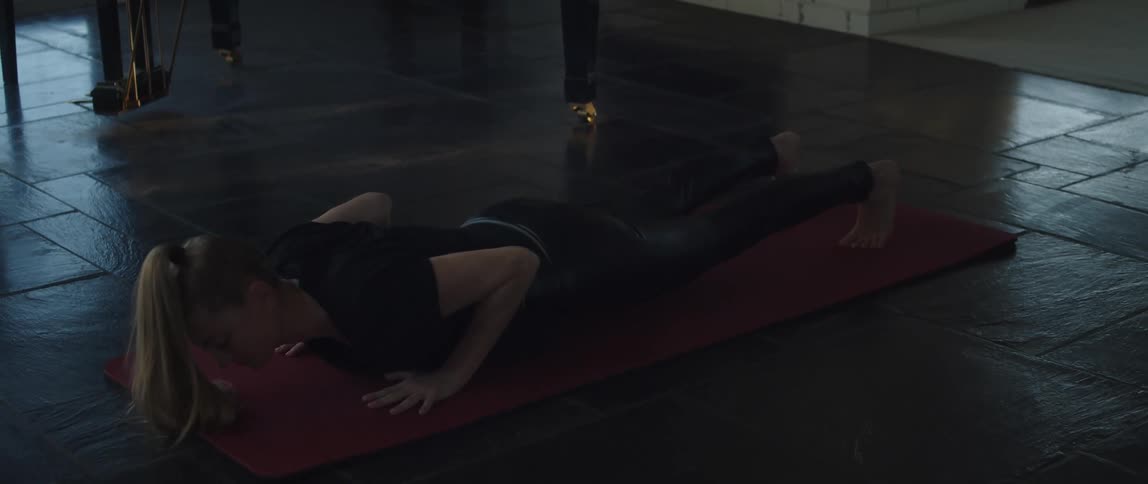 A woman is doing push up on an exercise mat on the floor when she stops to rest