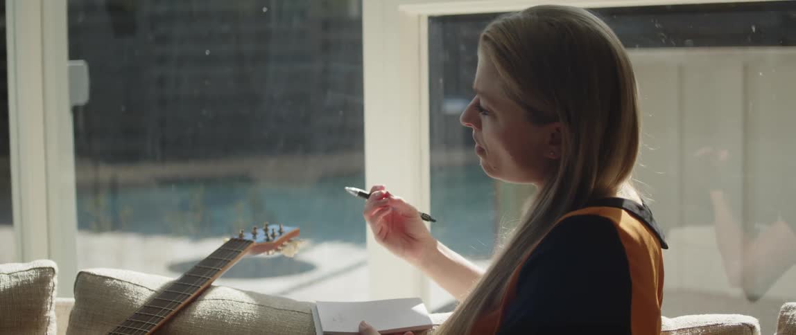 A woman is writing near her guitar