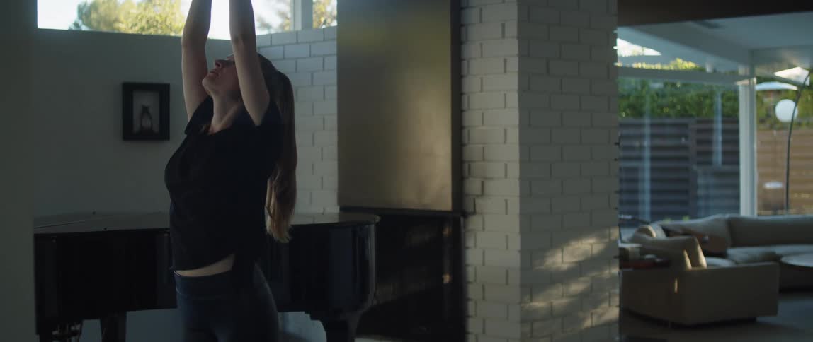 A woman does yoga exercises in a house during the day