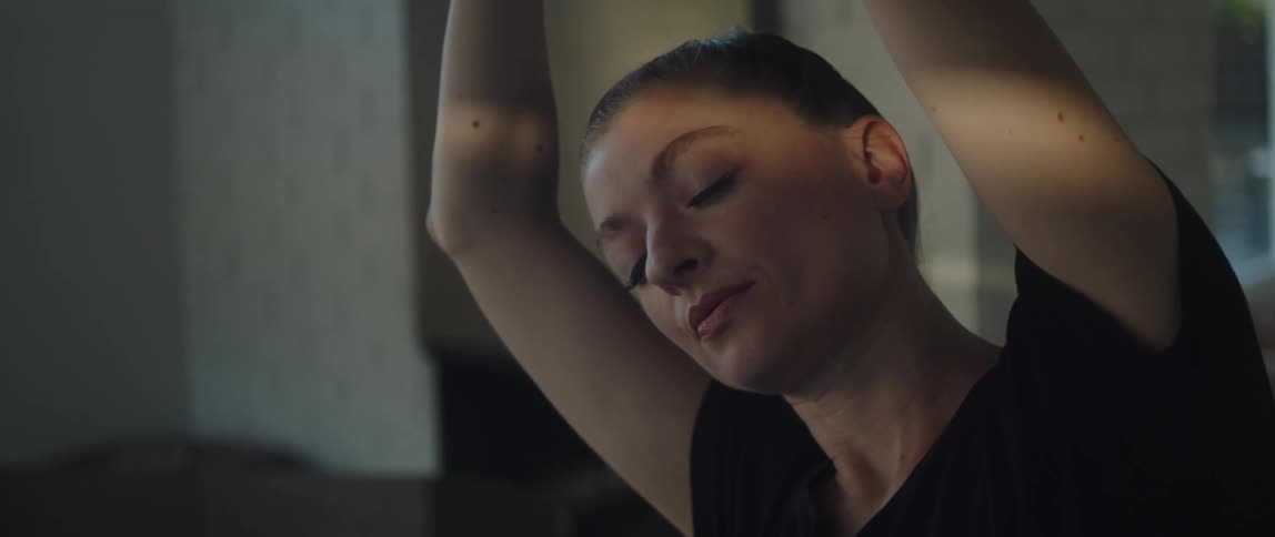 A relaxed woman doing a yoga pose and stretching with her eyes closed