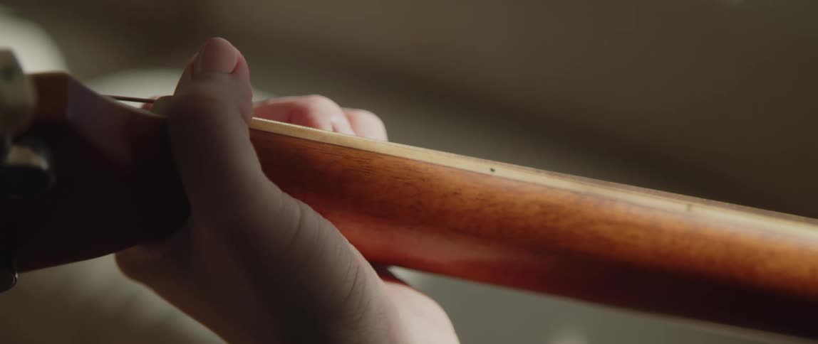 A person playing strings on a guitar with their fingers