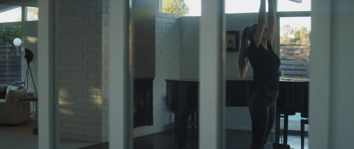 A woman wearing a black shirt and pants doing yoga raising her arms upwards and then to the middle of her chest