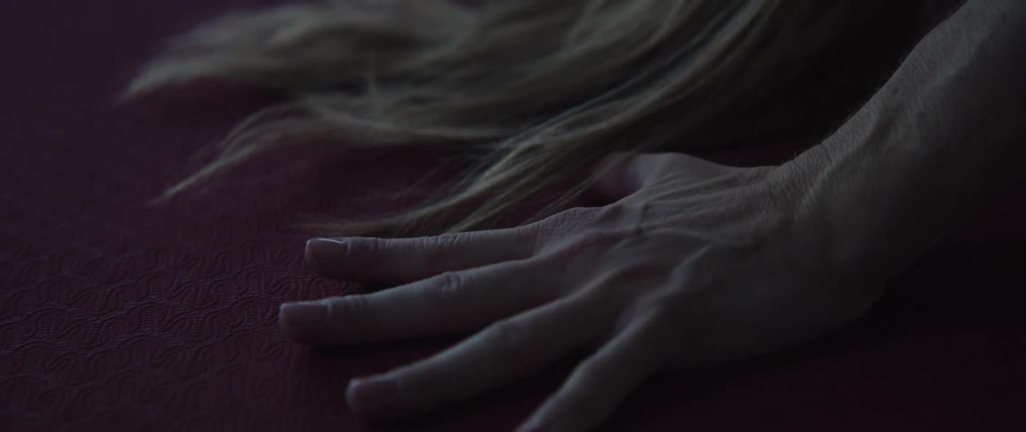 A womans hand and long blonde hair on a yoga mat