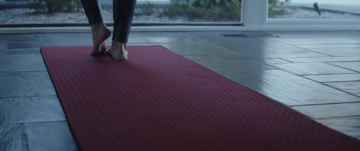 Close up of the foot of a woman practicing yoga over a mat at home in the morning