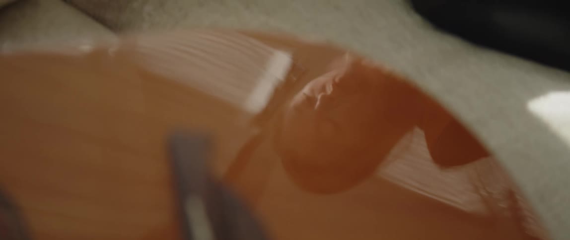 A reflection of a womans head on shiny surface of an acoustic guitar