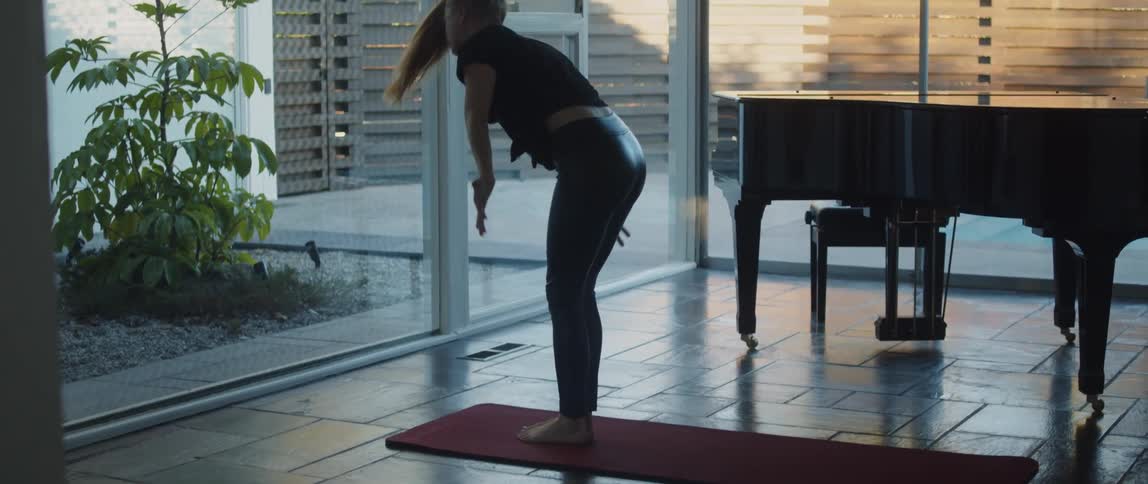 A female doing yoga on a mat indoors