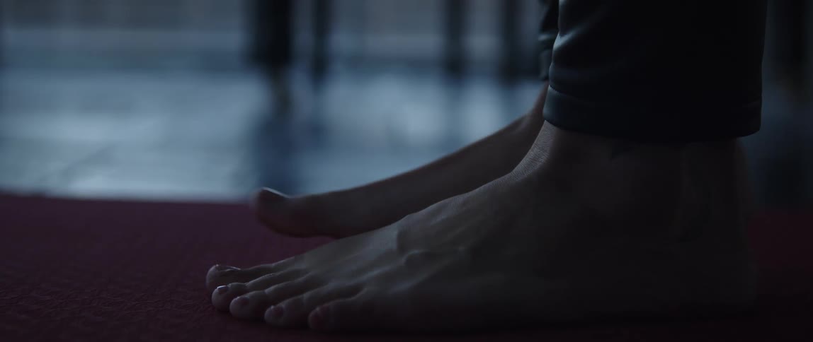 Woman in black yoga pants steps on yoga mat barefoot