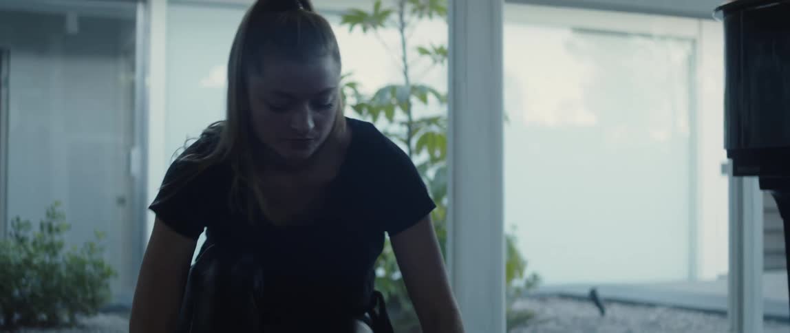 A woman with a ponytail rolling up a yoga mat at home