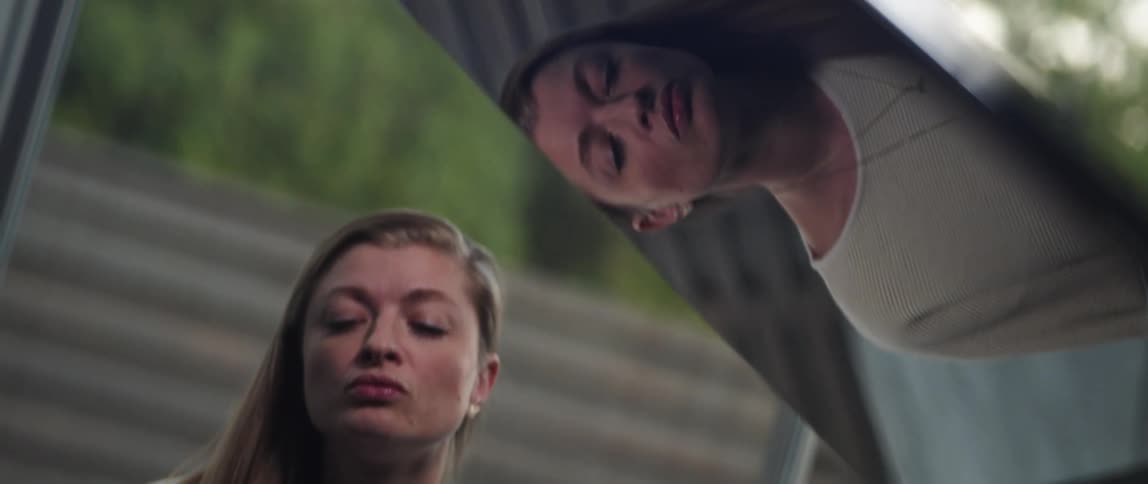 Woman in white sweater and necklace plays grand piano and is reflected on lid