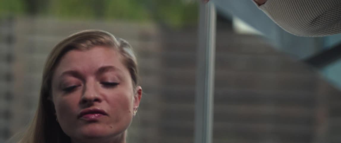 A blonde woman in a beige sweater singing with her eyes partly closed