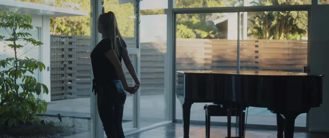 A woman is stretching indoors near a piano