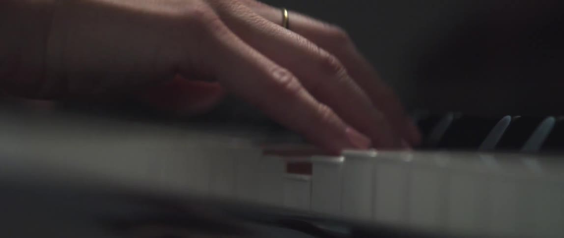 View of a womans hands as her fingers are pressing the keys of a piano as she plays