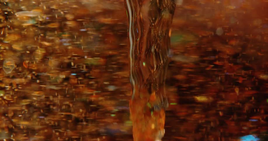 Orange particles spin and swirl around and along clear column