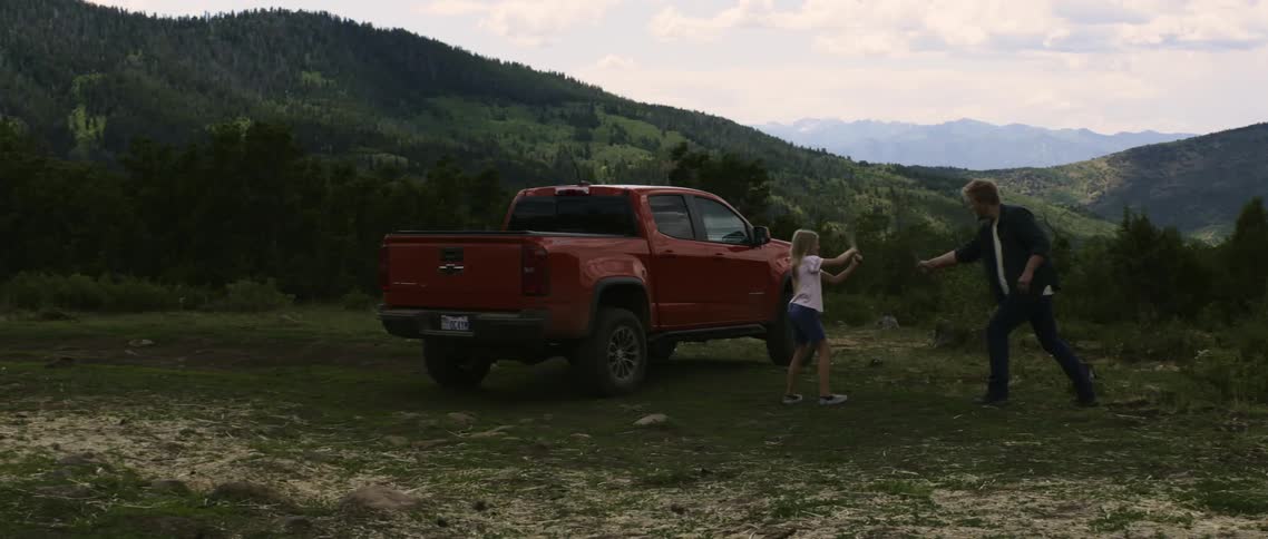 Father and daughter playing on the countryside next to a red pickup truck