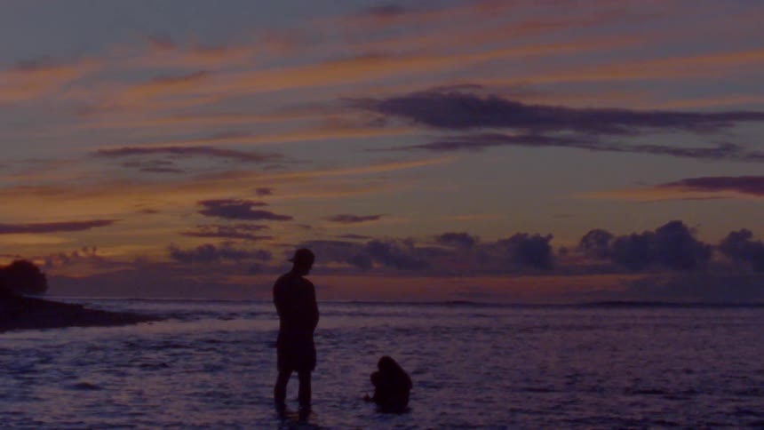 Silhouette of a family bathing on the shoreline of a beach at evening caught on vintage film