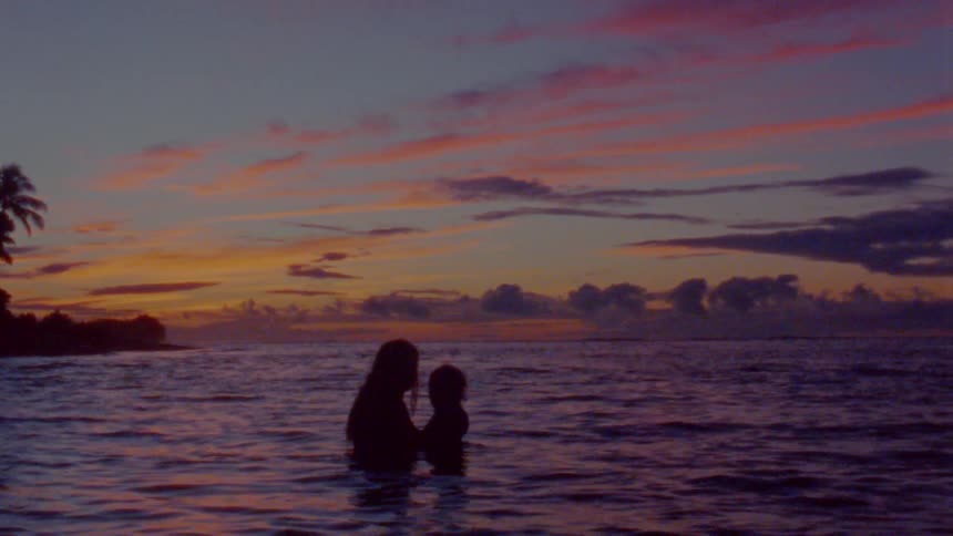 A mother is holding their child in the ocean