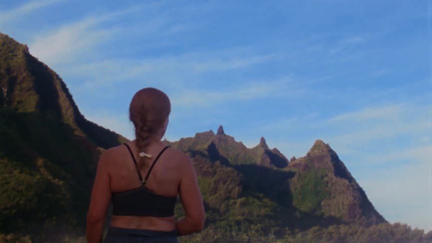 The backside of a woman standing looking at mountains against a blue sky
