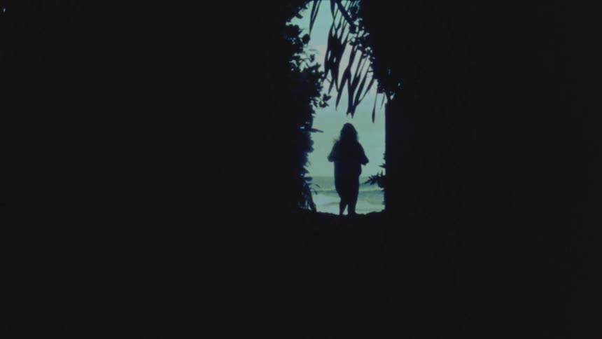 Woman with shirt and shorts runs through forest to the beach