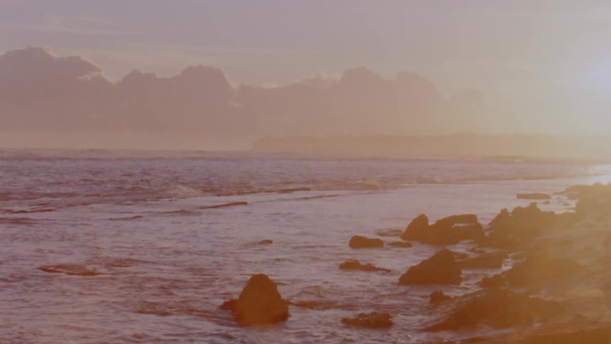 Waves crash against the shore at sunrise