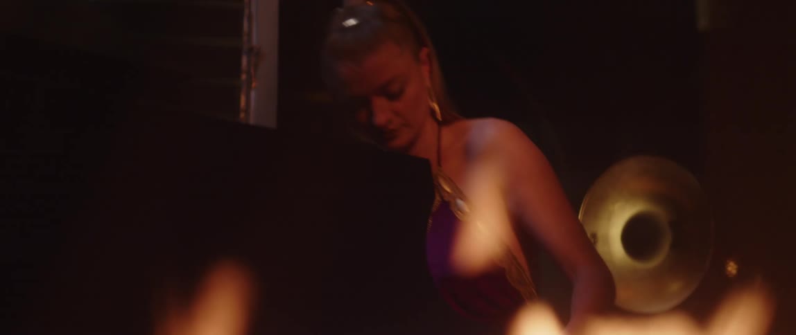 A woman sits down to play the piano in front of the fire