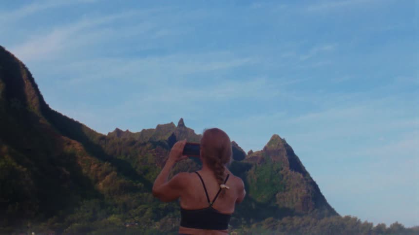 A woman is taking photos of the mountains with her phone