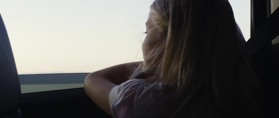 A girl rides in the back seat of the car