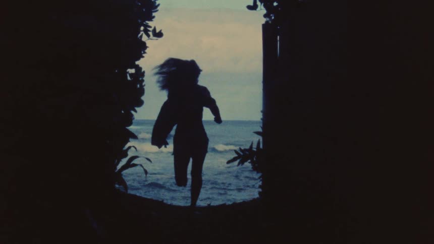 A womans silhouette running towards the ocean
