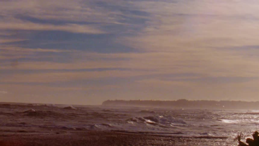 Slow motion footage of golden sunlight reflecting over the waves near the tropical coast caught on vintage film