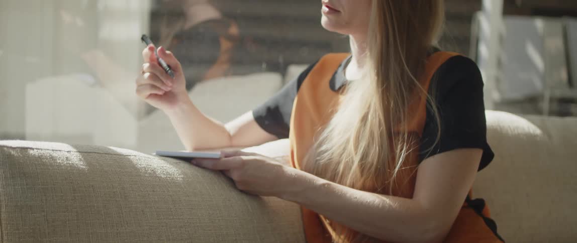 A shot of a guitar and then a womans black leather pants while she sings and writes on paper