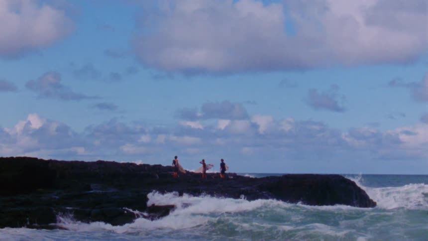 There are people hanging around the ocean and are about to surf
