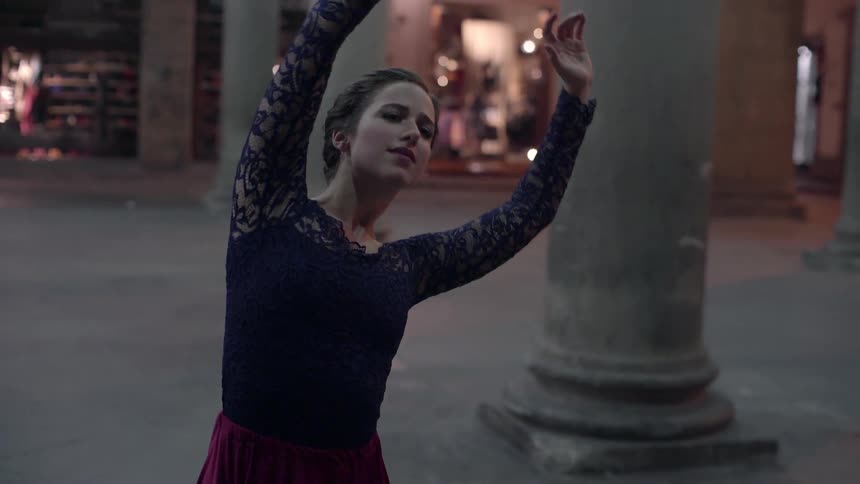 Women dance outside near large pillars