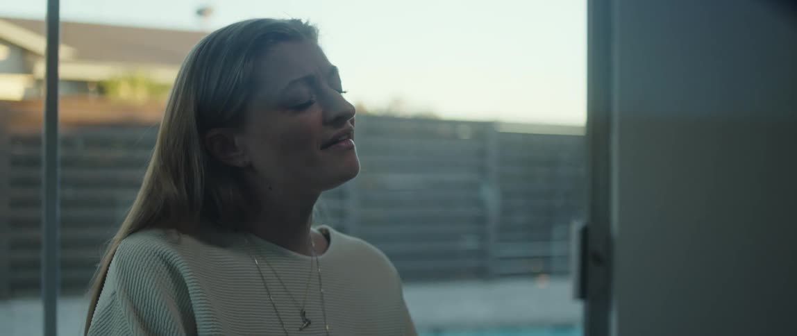 A woman is singing indoors next to a window