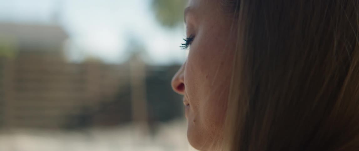Side profile of woman with brown hair looking down and closing her eyes