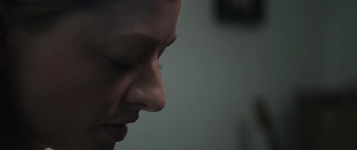 Close up of the face of a woman singing in a dimly lit room