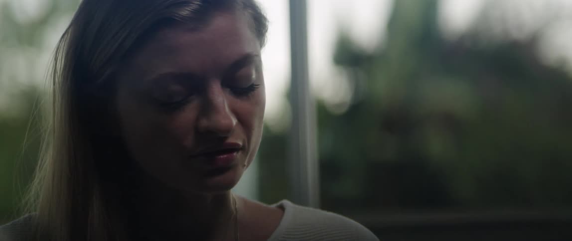 Close up of the face of a young woman inspiredly singing near a window at evening