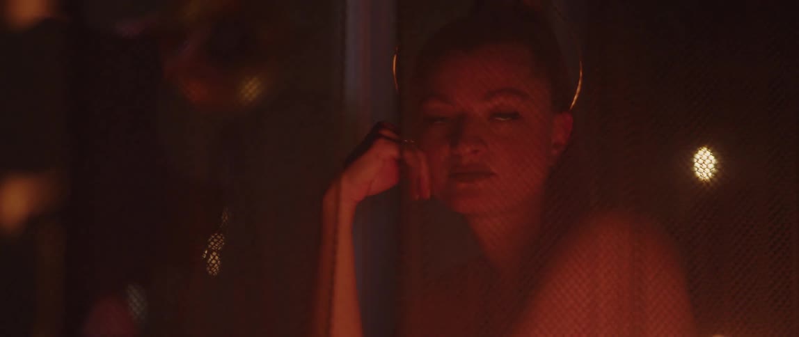 Young woman sitting behind a veil looking at a fire at night