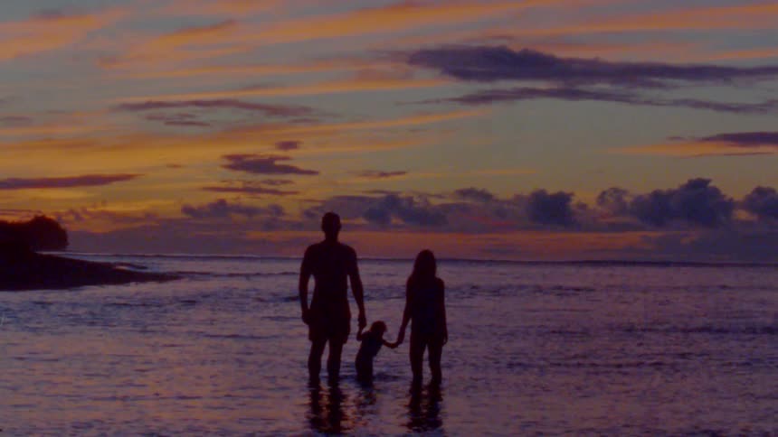 Silhouette of a family bathing on the shoreline of a beach at evening caught on vintage film