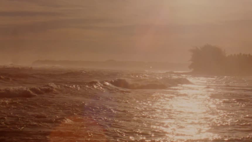 Landscape of ocean waves breaking agains the shore at sunset