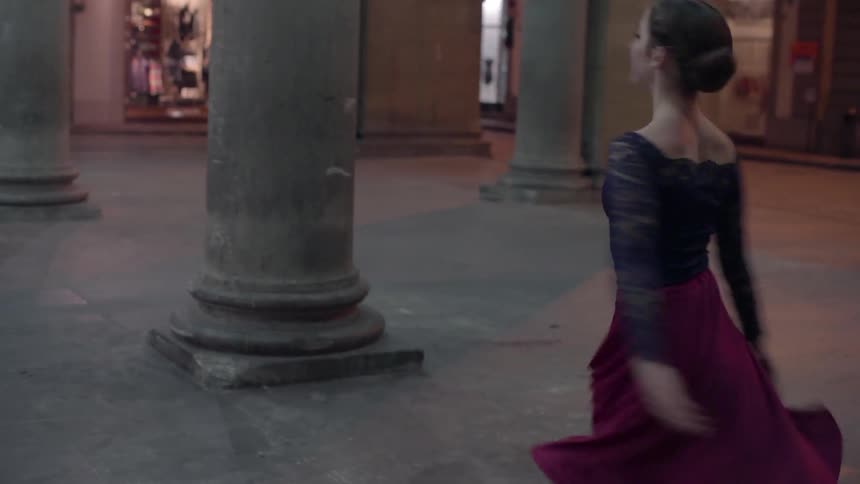A group of women dance near large pillars