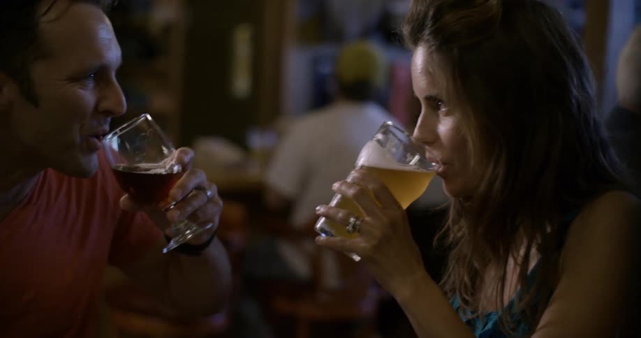 A man and woman have a toast while sitting at a table