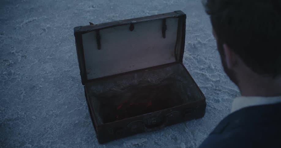 A man is sitting outdoors and looking in a box