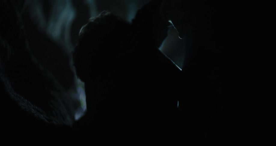 A man is crawling through a cave with the sunlight behind him