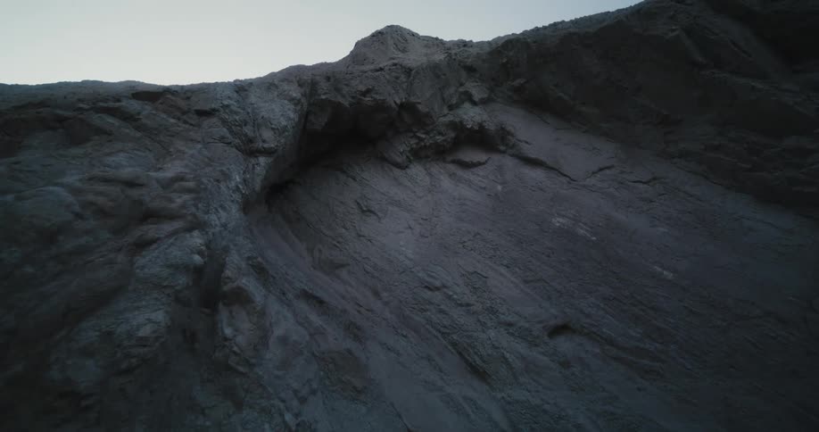 Looking up at a rocky ledge on a mountains under a hazy sky