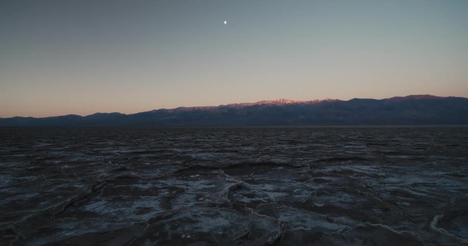 The moon shines over a desert landscape
