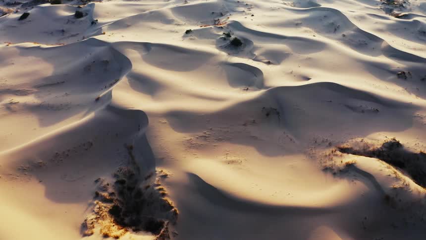Aerial view of gentle white sand dunes in the desert at morning