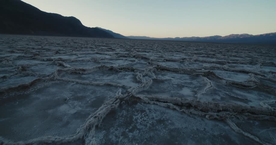 Rough dry ground stretches between mountains to foggy horizon