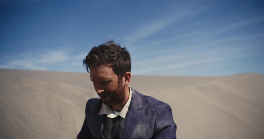 A stressed man in a dirty suit in a desert