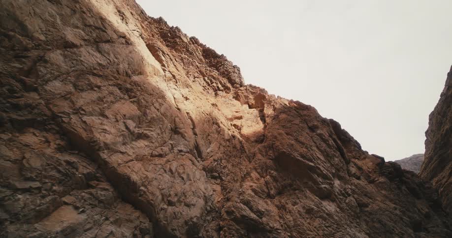 Walking through a canyon in the desert looking at the bare rock walls at morning